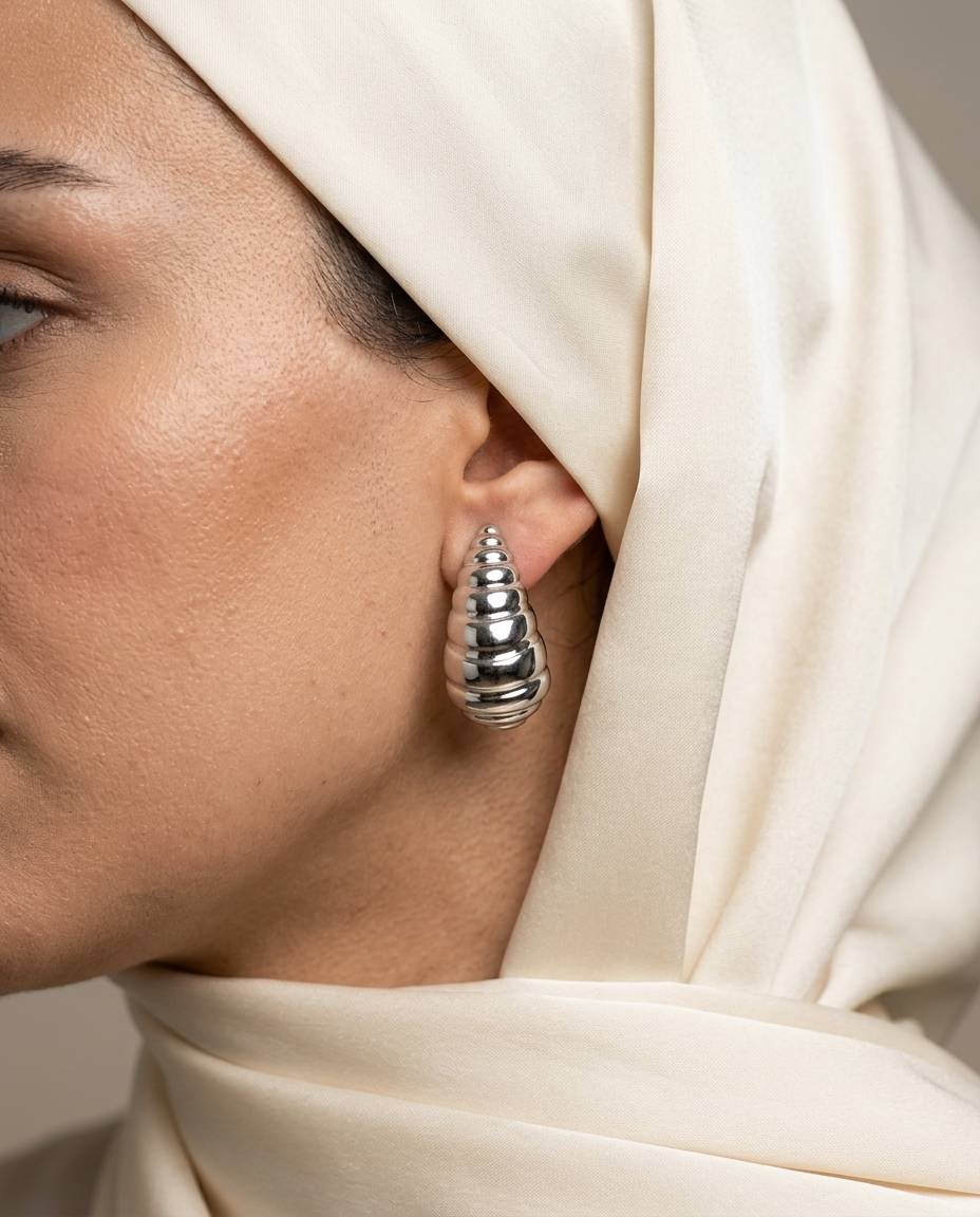 گوشواره میخی طرح کروسان نقره‌ای روی گوش با طراحی برجسته