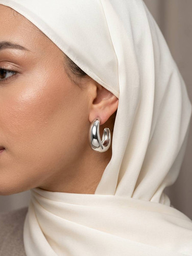 گوشواره C-شکل تپل نقرهای با سطح صیقلی روی گوش مدل با استایل شیک.